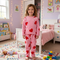 Child wearing pink heart-patterned pajamas in a colorful bedroom.