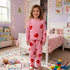 Child wearing pink heart-patterned pajamas in a colorful bedroom.