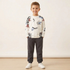 Child wearing a white sweatshirt with colorful graphics and dark pants on a plain background