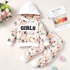 A two-piece girls' outfit set featuring a long-sleeve hooded sweatshirt and matching pants, both decorated with a peach and green floral pattern on a white background. The hoodie has a white hood and a white chest panel with the word 'GIRLS' printed in black.