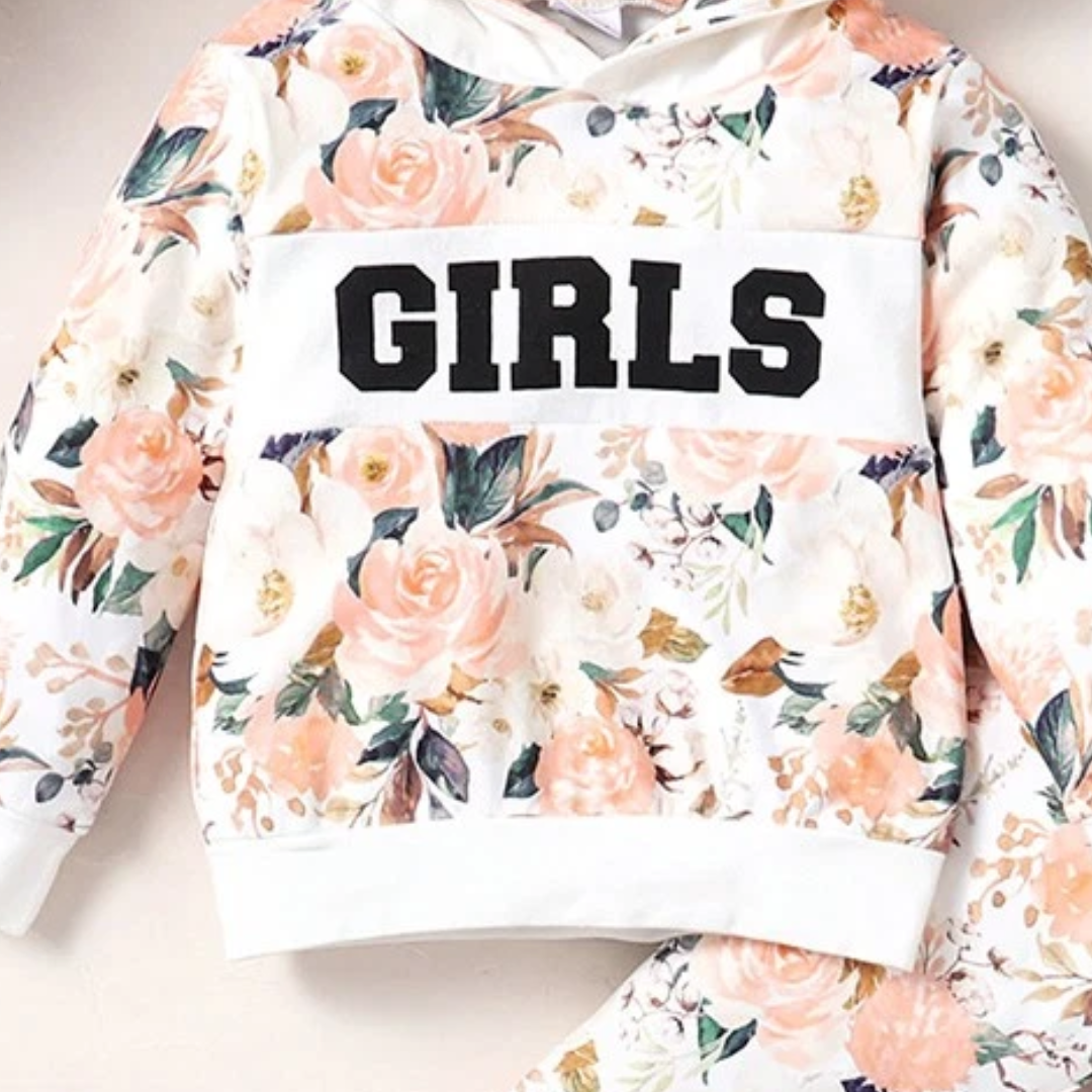 A girls' floral hoodie sweatshirt with a white chest panel featuring the word 'GIRLS' in bold black letters. The hoodie has a watercolor-style print of peach, pink, and white roses with green leaves on a cream background.