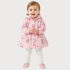 A toddler girl wearing a pink hooded raincoat with a floral print, white leggings, and pink slippers, standing against a light gray background.