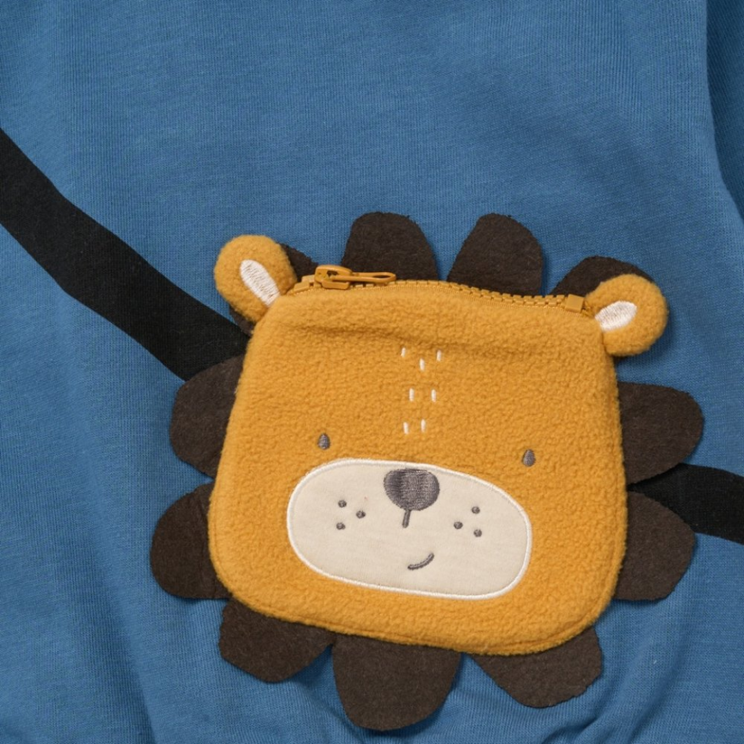 A small lion-face zip pouch in mustard yellow and brown, placed on a blue fabric background.