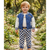 A toddler stands on a garden path wearing a blue quilted bomber jacket with white sleeves, a white shirt, and blue-and-white checkered pants.