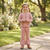 Little girl posing in a sunny park while wearing a cozy autumn knitwear two-piece set with brown boots.