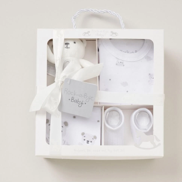 Baby gift set with white bear, clothes, and booties in a box on a light background