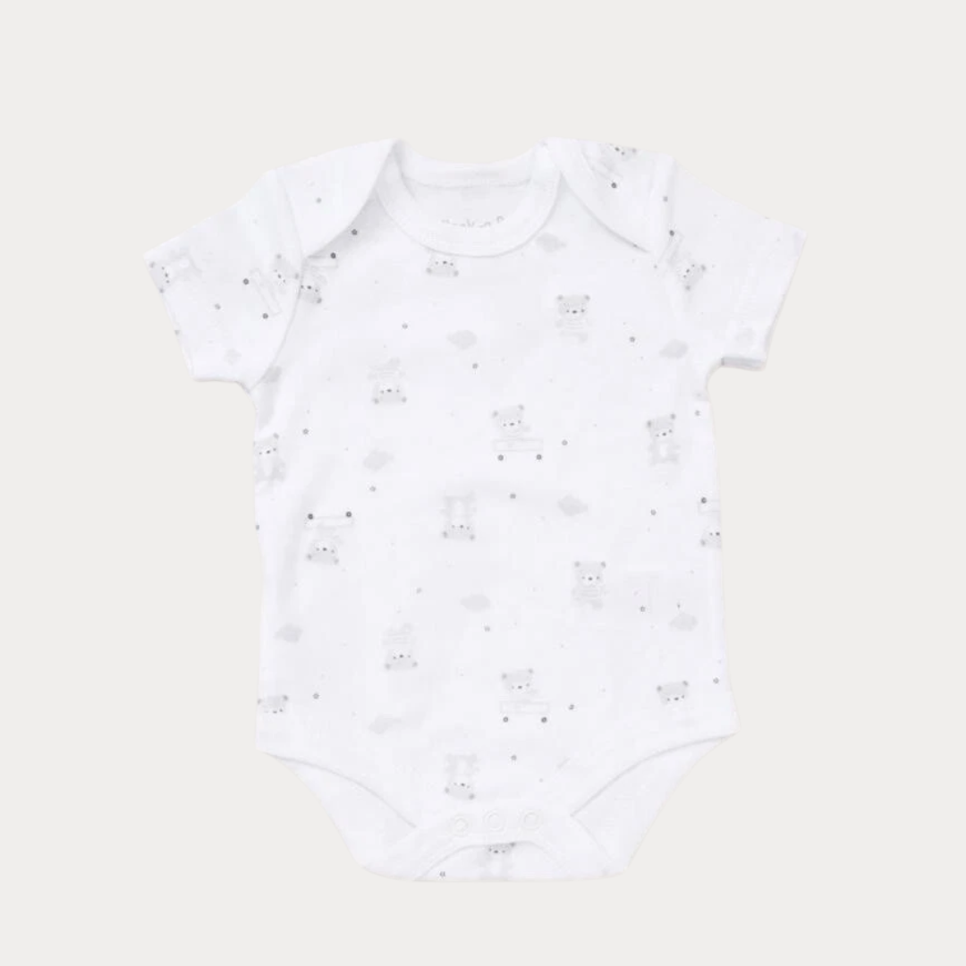 White baby onesie with small print on a light beige background