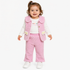 A toddler girl wearing a pink textured knit vest and matching pants over a white long-sleeve shirt, standing against a plain white background.