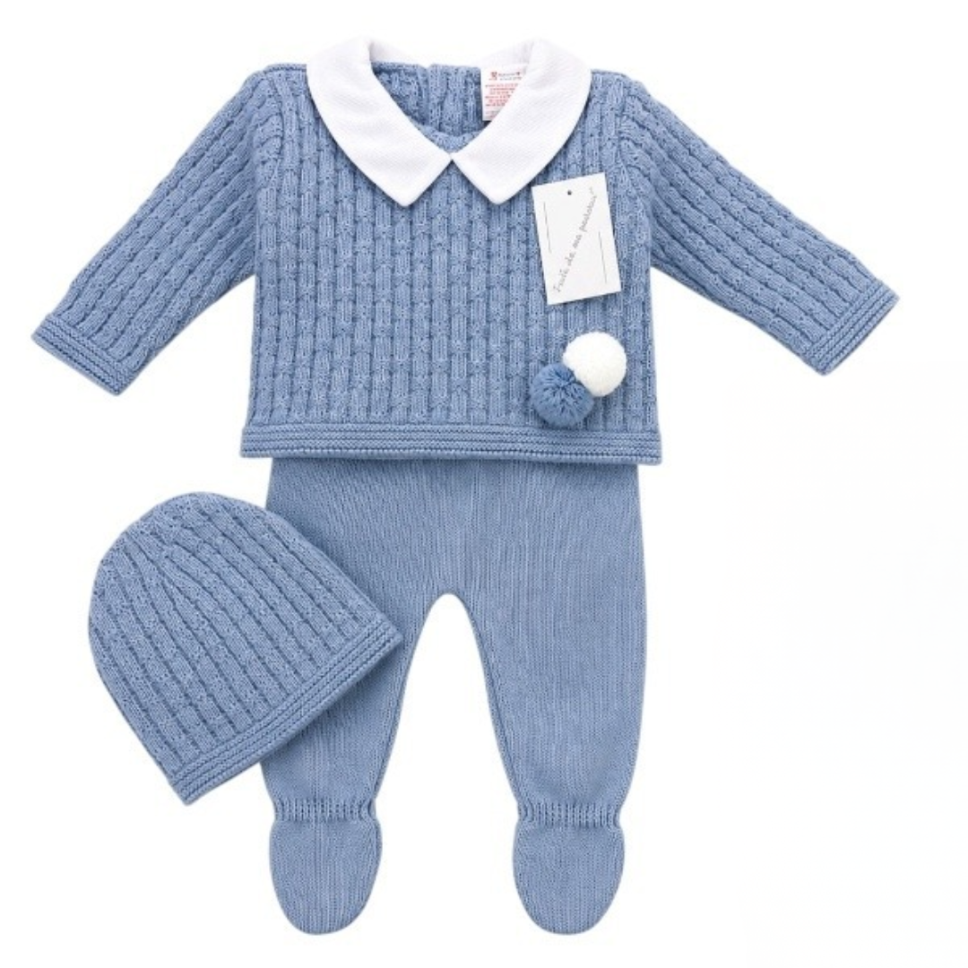 Blue cable-knit baby outfit set featuring a long-sleeve sweater with a white Peter Pan collar and pom-pom accents, matching footed leggings, and a ribbed beanie hat on a white background.