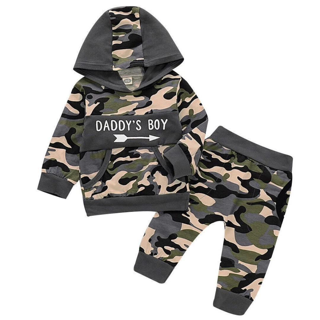 A two-piece baby clothing set featuring a camouflage hoodie and matching pants. The hoodie has a green, beige, and black camo pattern with a solid dark gray hood and cuffs, and a front patch reading 'DADDY'S BOY' in white text.