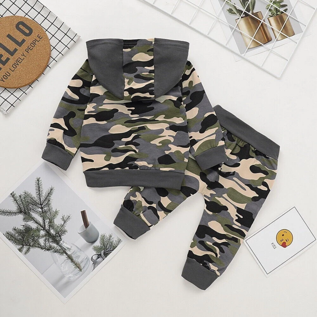 A baby two-piece camouflage outfit laid flat on a white background, featuring a hooded long-sleeve top and matching pants. The camouflage pattern mixes beige, green, black, and gray, with solid dark gray trim on the hood, cuffs, and waistband.
