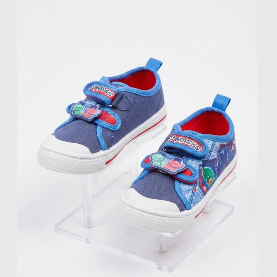A pair of children's blue canvas sneakers with white rubber soles, featuring colorful cartoon character patches on the velcro straps and a red interior lining, displayed on clear acrylic stands against a white background.