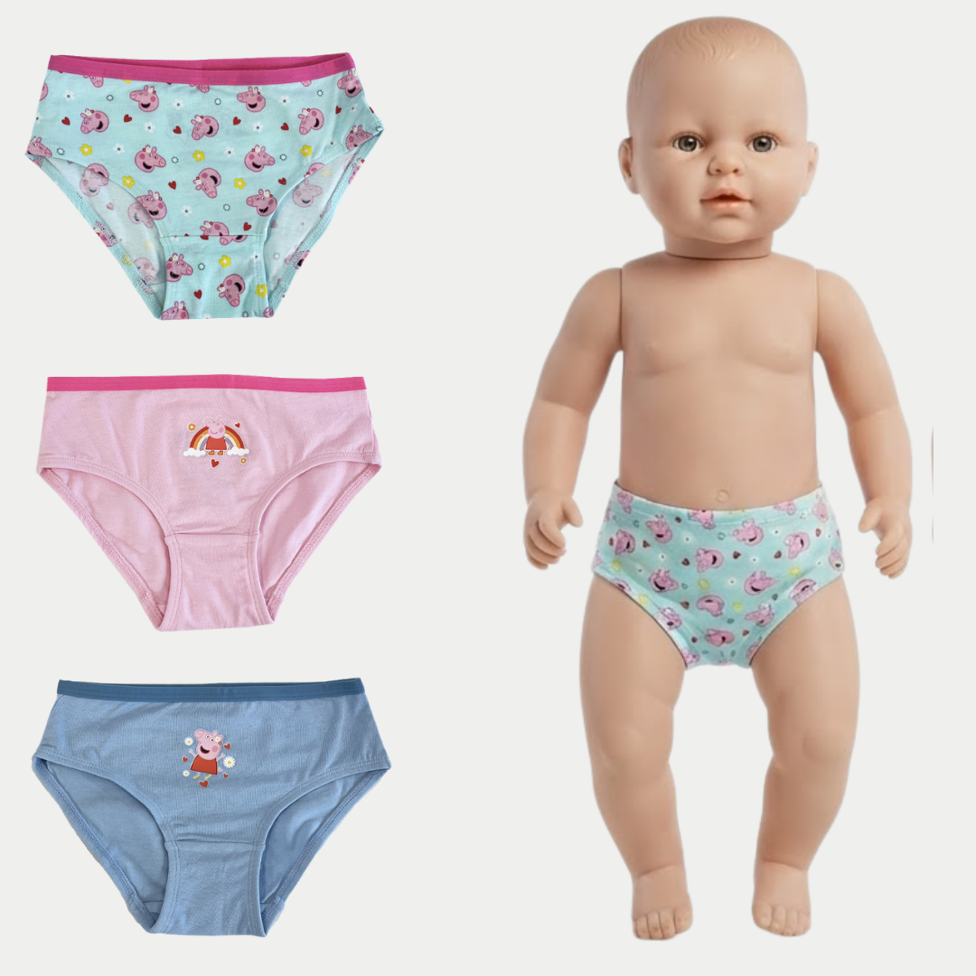 Three pairs of children's underwear shown on a plain light background, alongside a baby doll wearing one pair. The set includes a light blue pair with pink cartoon prints and a pink waistband, a pink pair with a small dog graphic, and a blue pair with a small character graphic.