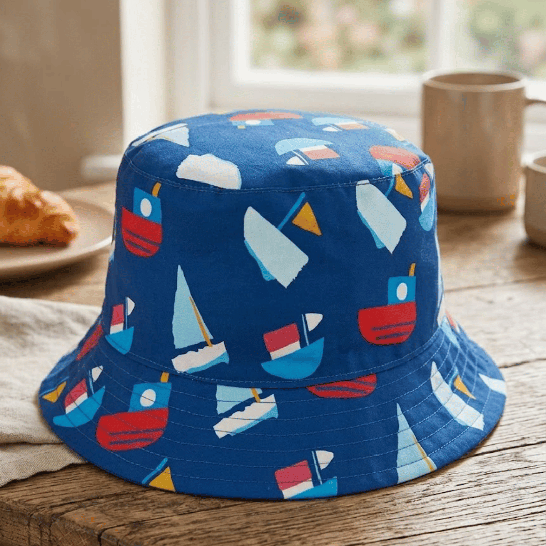 Blue bucket hat with colorful boat pattern on a wooden surface