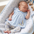 Baby in a blue dress with a rabbit design, lying on a soft surface with toys.
