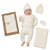 A baby wearing a cream-colored ribbed knit outfit set, including a hat with pom-pom, long-sleeve top, pants, and booties, shown next to the matching gift box and folded blanket on a white background.