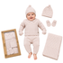 A baby outfit set displayed on a white background, featuring a smiling baby wearing a cream-colored knit sweater, pants, hat, and mittens. Surrounding the baby are the individual pieces, a folded matching blanket, and the product box.