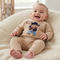 A smiling baby wearing a beige knit romper with a cowboy bear graphic, sitting in a cream-colored textured bouncer chair.
