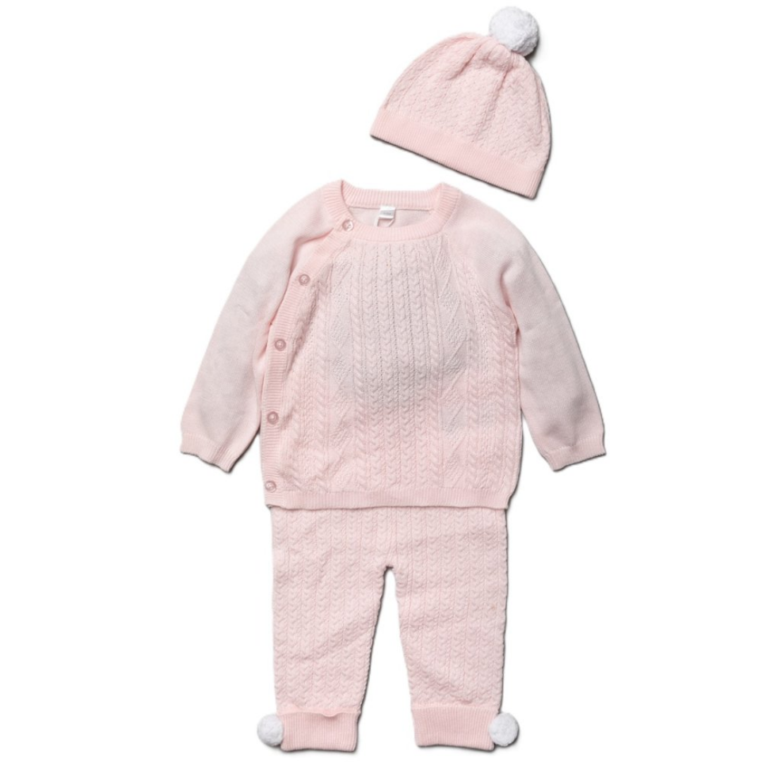 A baby girl's three-piece knit outfit set in pale pink, featuring a long-sleeve button-front cardigan, matching footed pants with white pom-pom details, and a matching beanie with a white pom-pom, displayed on a clean white background.
