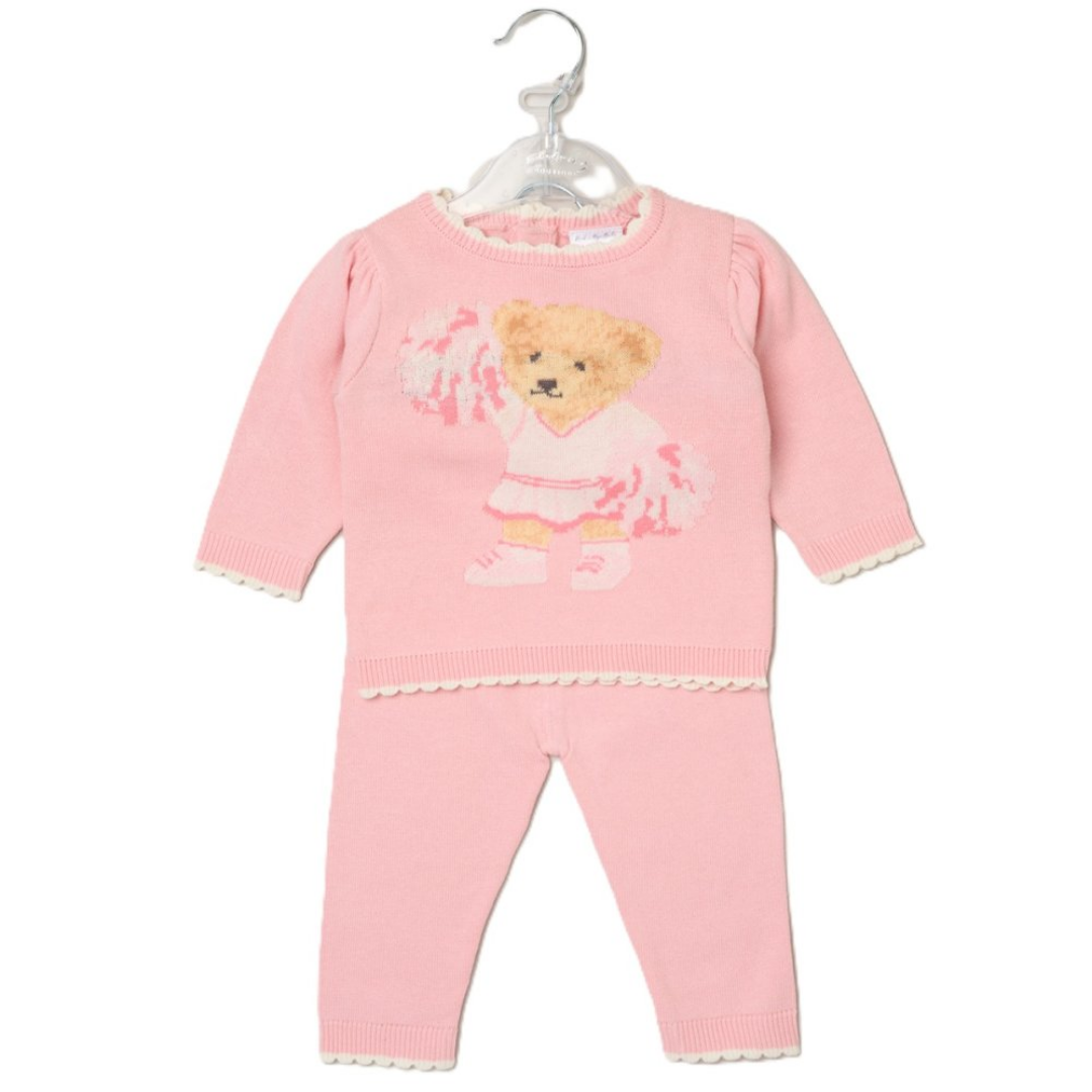 A baby girl's two-piece knit outfit in light pink, featuring a long-sleeve top with a teddy bear graphic and matching pants, hanging on a clear plastic hanger against a white background.