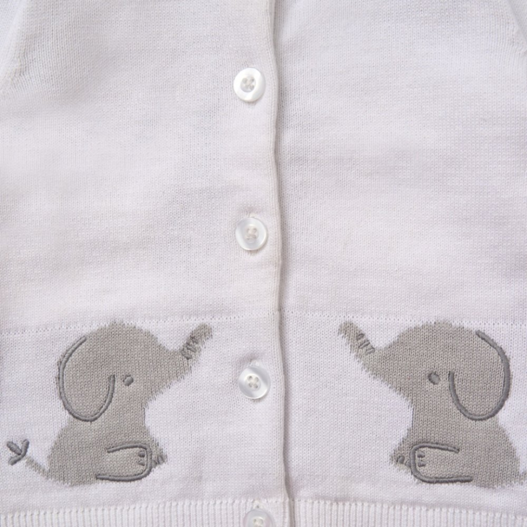 Close-up of a white knit cardigan with white buttons and gray embroidered elephant motifs on both sides near the hem.