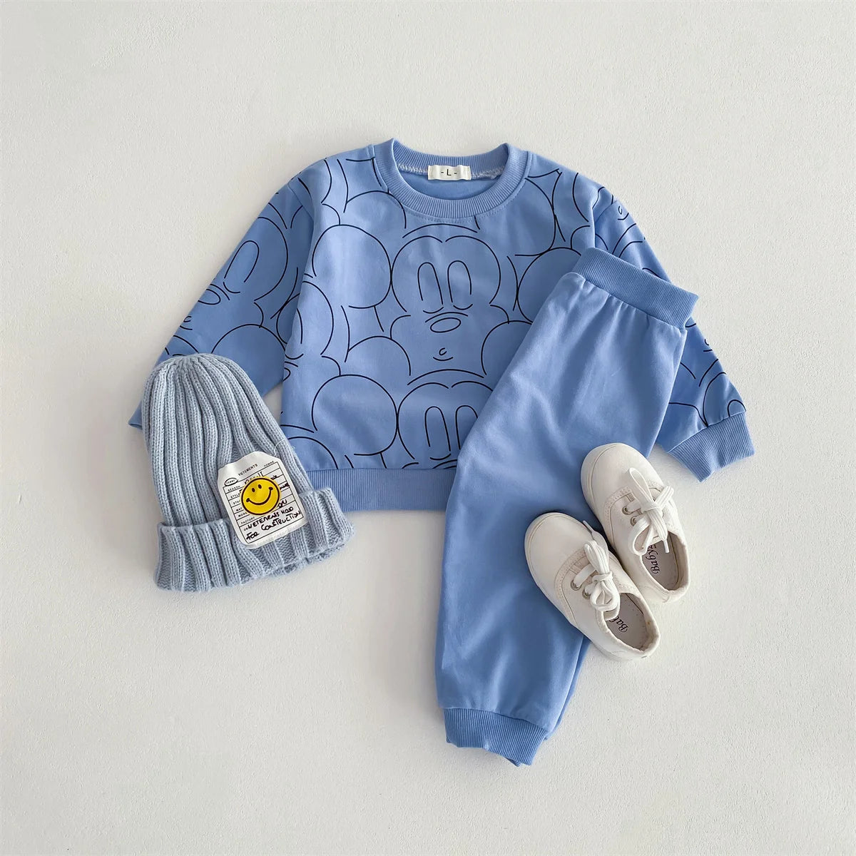 Blue children's outfit with matching hat and shoes on a light gray background