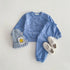 Blue children's outfit with matching hat and shoes on a light gray background