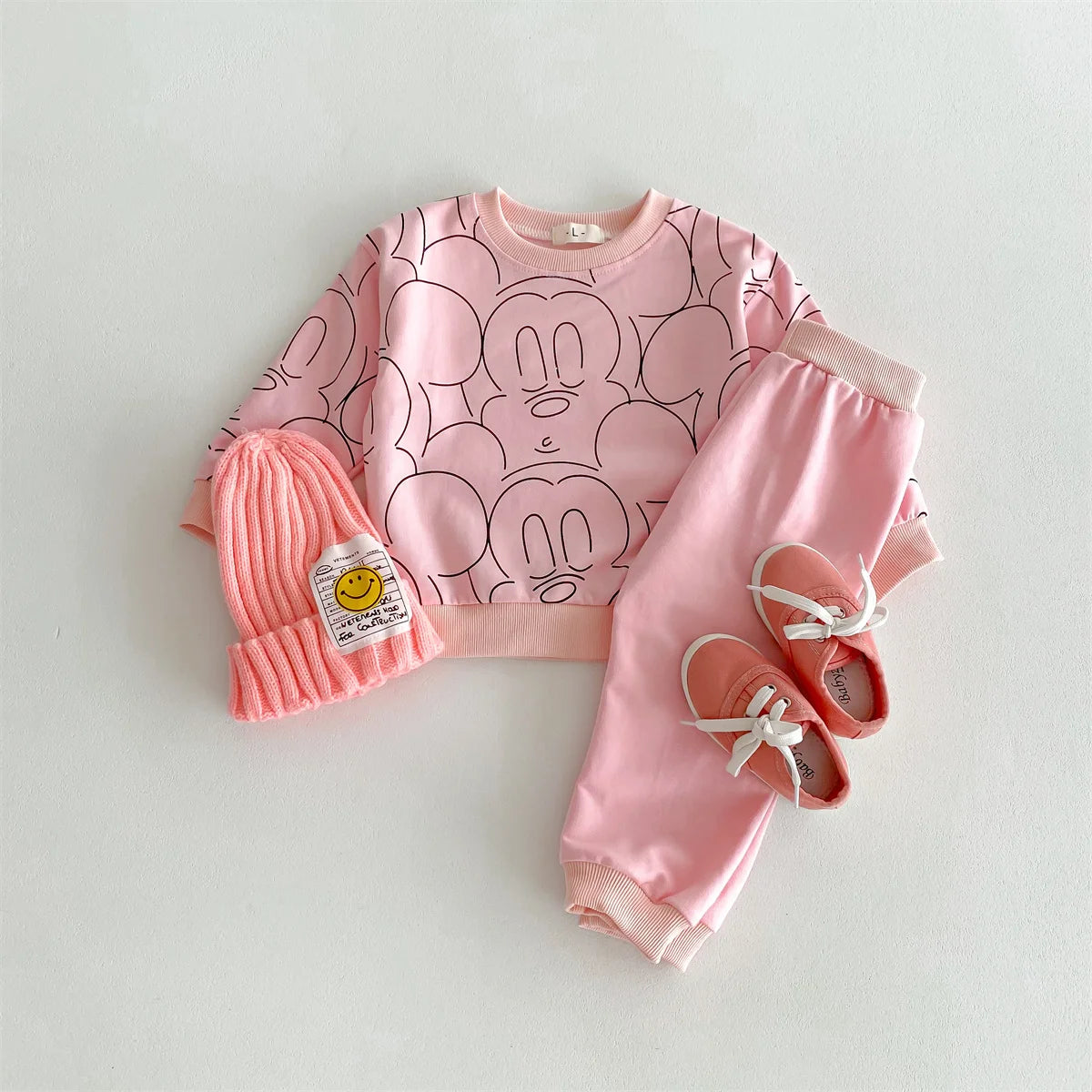 Pink children's outfit with matching hat and shoes on a light gray background