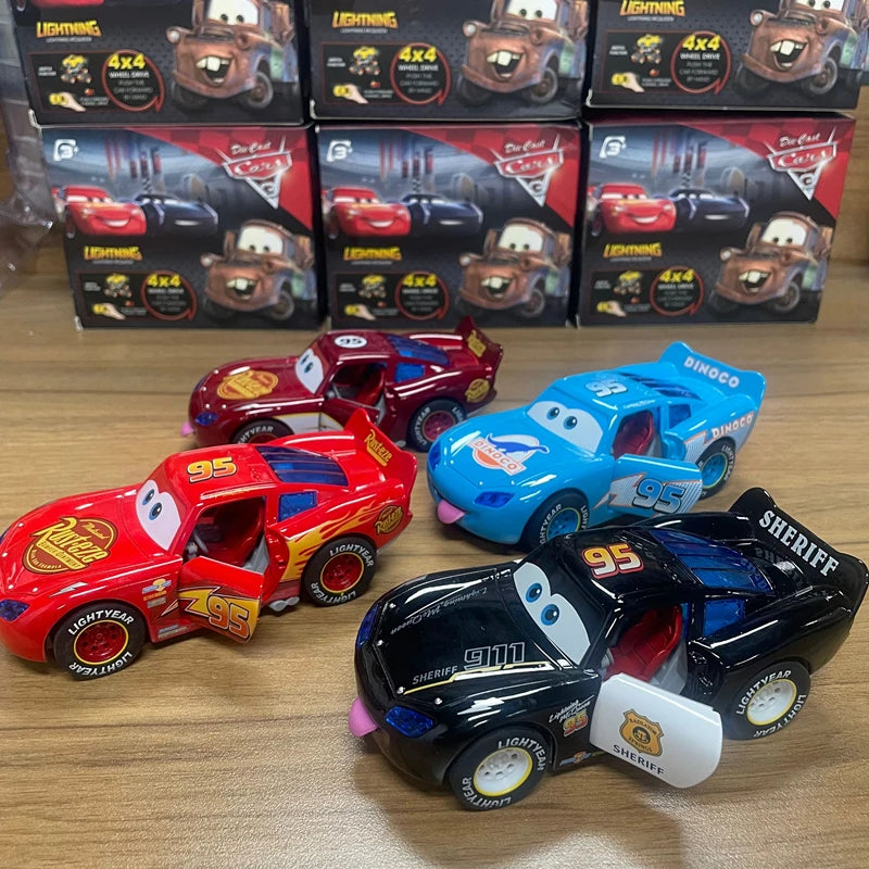 Toy cars including Lightning McQueen and Mater with their packaging on a wooden surface