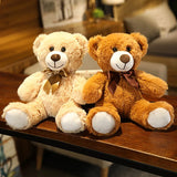 Two teddy bears, one beige and one brown, sitting on a wooden surface with a blurred indoor background.