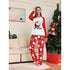 Woman wearing Christmas-themed pajamas in a living room with a decorated tree.