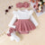 Baby outfit with white top, red and white checkered skirt, white tights, and headband on a textured surface.