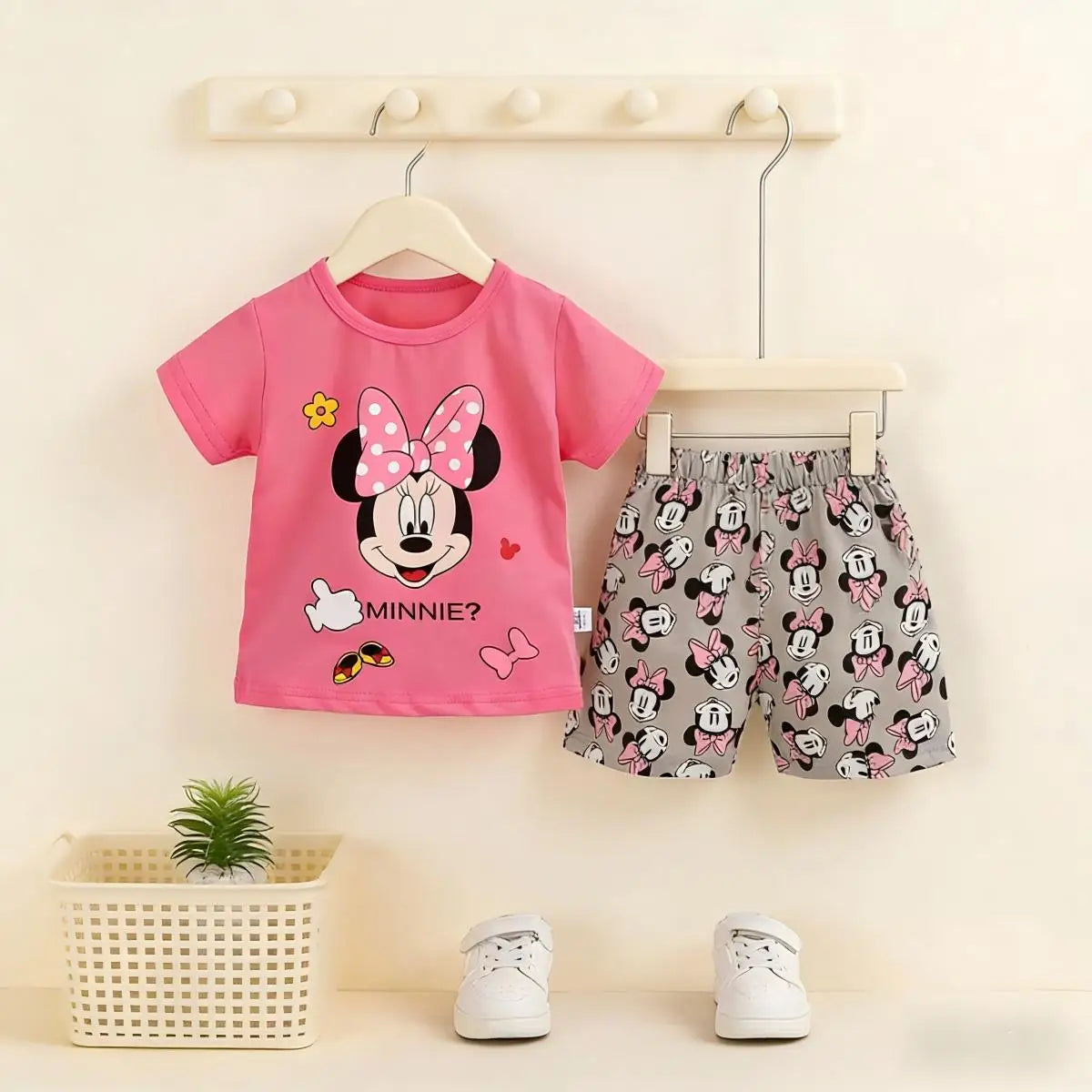 Children's outfit with pink shirt and patterned shorts on hangers against a light background