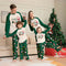 Family of four wearing matching Christmas pajamas in a living room with a decorated tree.