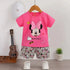 Pink t-shirt with Minnie Mouse design and gray shorts on a hanger against a white wall.