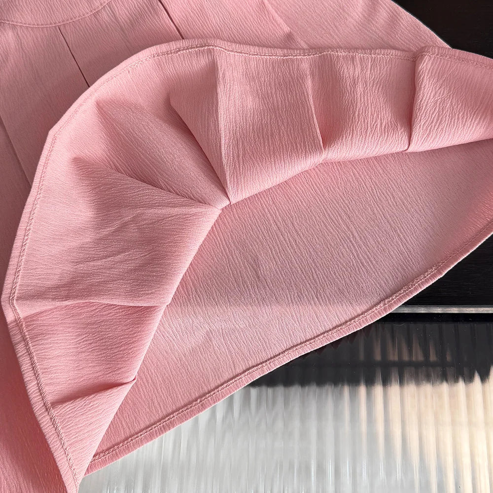 Close-up of a pink fabric with folds on a white surface
