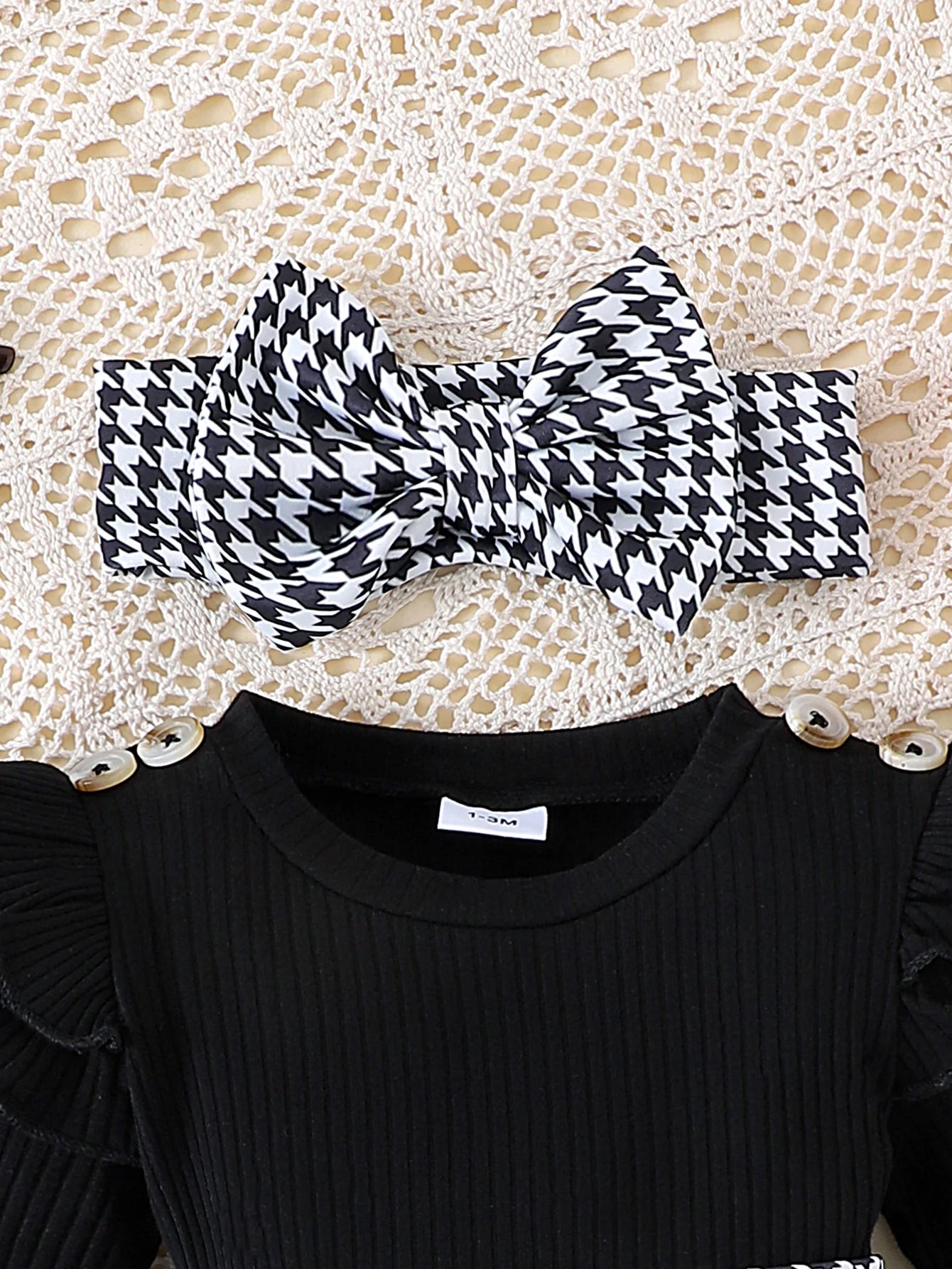 Black and white houndstooth patterned headband on a black top with a lace background