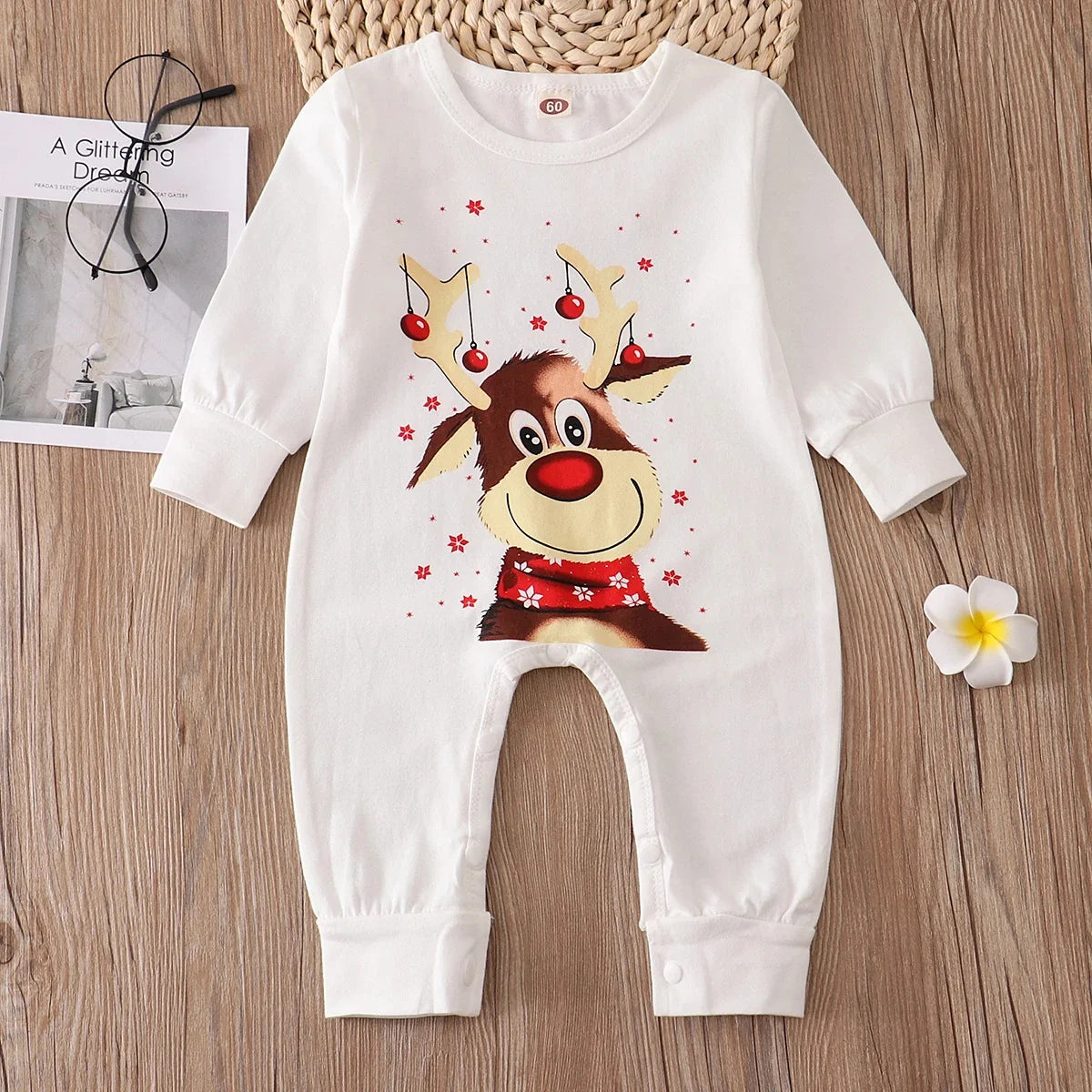 White baby romper with reindeer design on a wooden surface