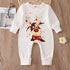 White baby romper with reindeer design on a wooden surface