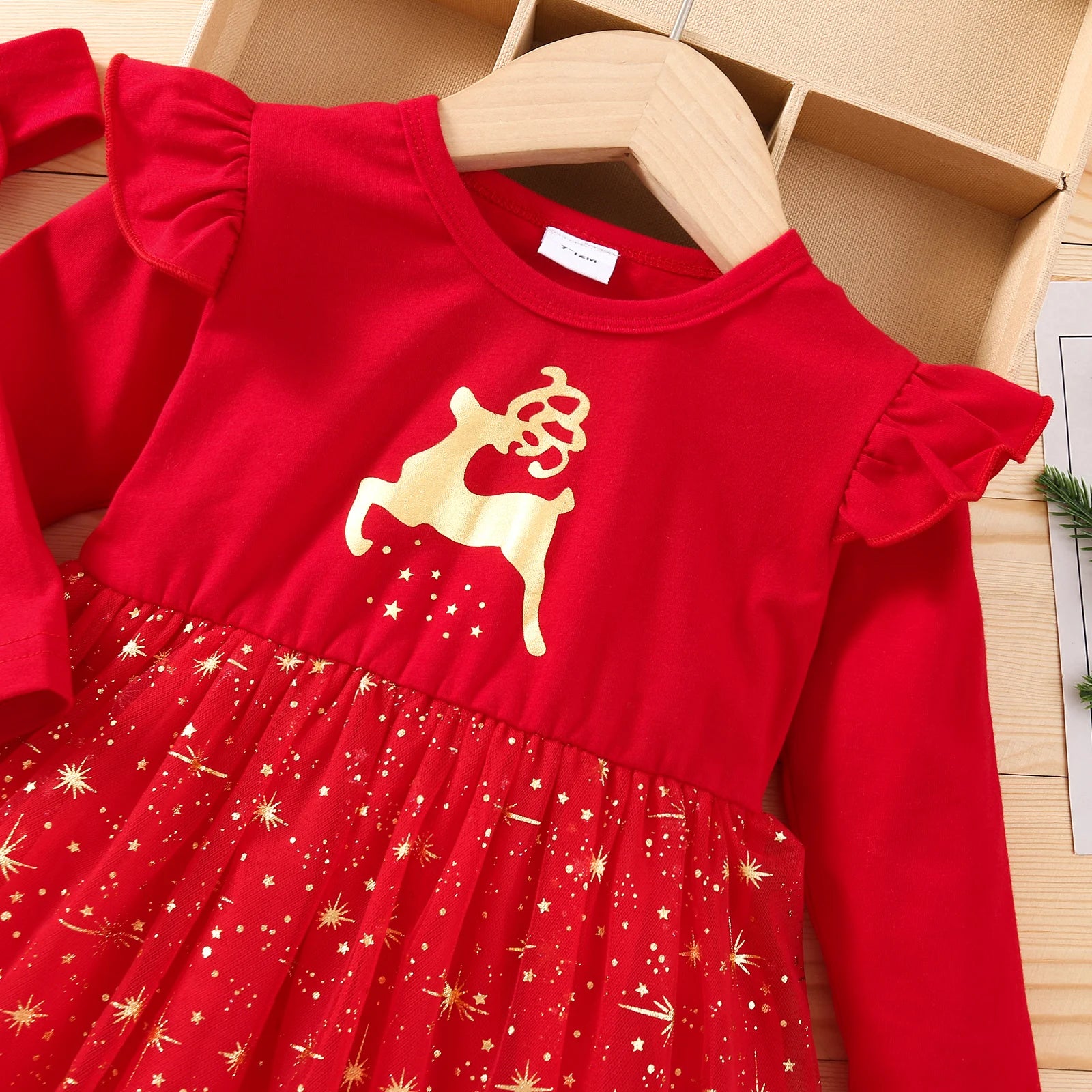Red dress with gold reindeer design on a wooden hanger