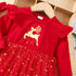 Red dress with gold reindeer design on a wooden hanger