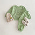 Green children's outfit with matching hat and shoes on a white background