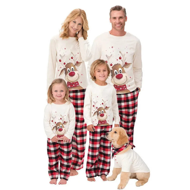 Family of four wearing matching Christmas pajamas with reindeer designs on a white background.