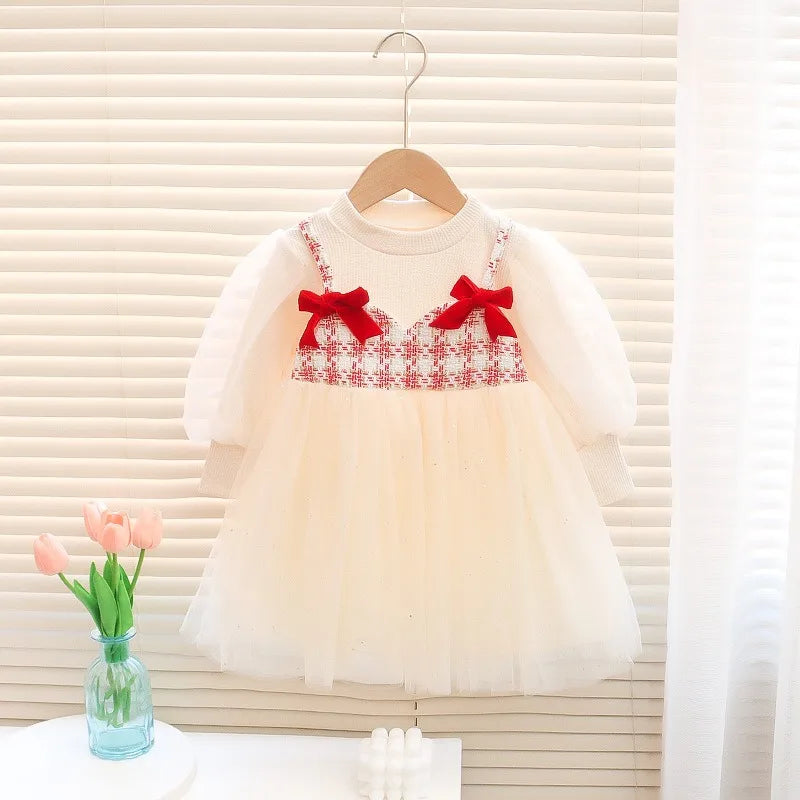 White dress with red bows on a hanger against a neutral background