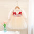 White dress with red bows on a hanger against a neutral background