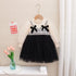 Children's dress with black and white pattern on a hanger against a neutral background