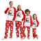 Family wearing matching Christmas pajamas with Santa Claus design.