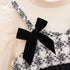 Close-up of a black bow on a patterned top with a beige background