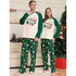 Two people wearing matching Christmas-themed pajamas in a living room setting.