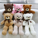 Six teddy bears in different colors with brown ribbons on a white surface.
